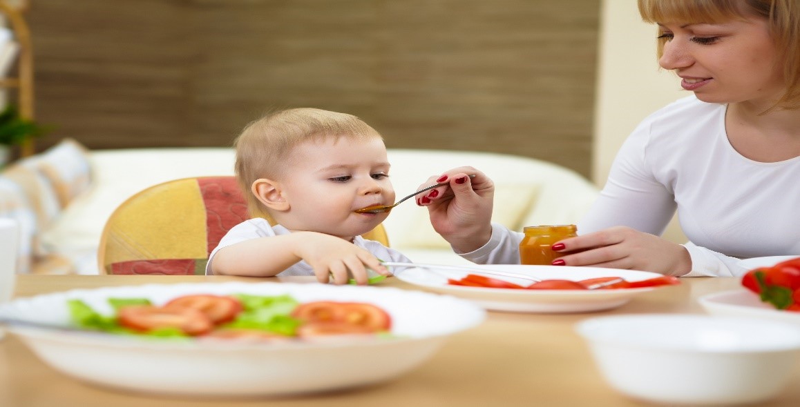 A mother feeding her baby some baby food by spoon